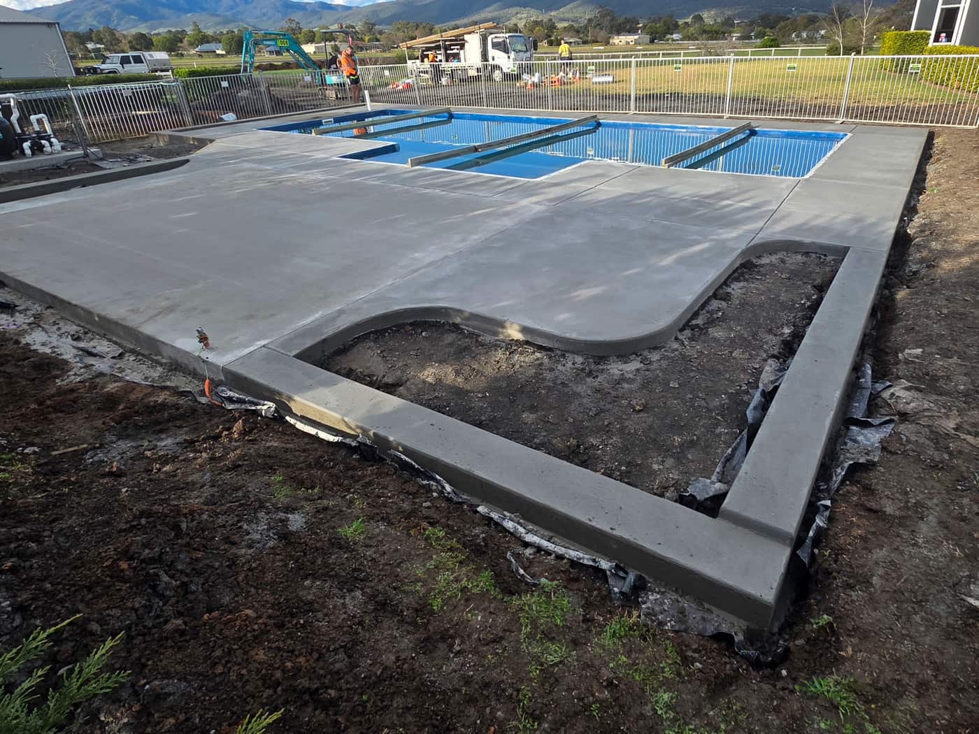 A finished concrete surround around an in-ground pool, with the thickened slab edge in the foreground